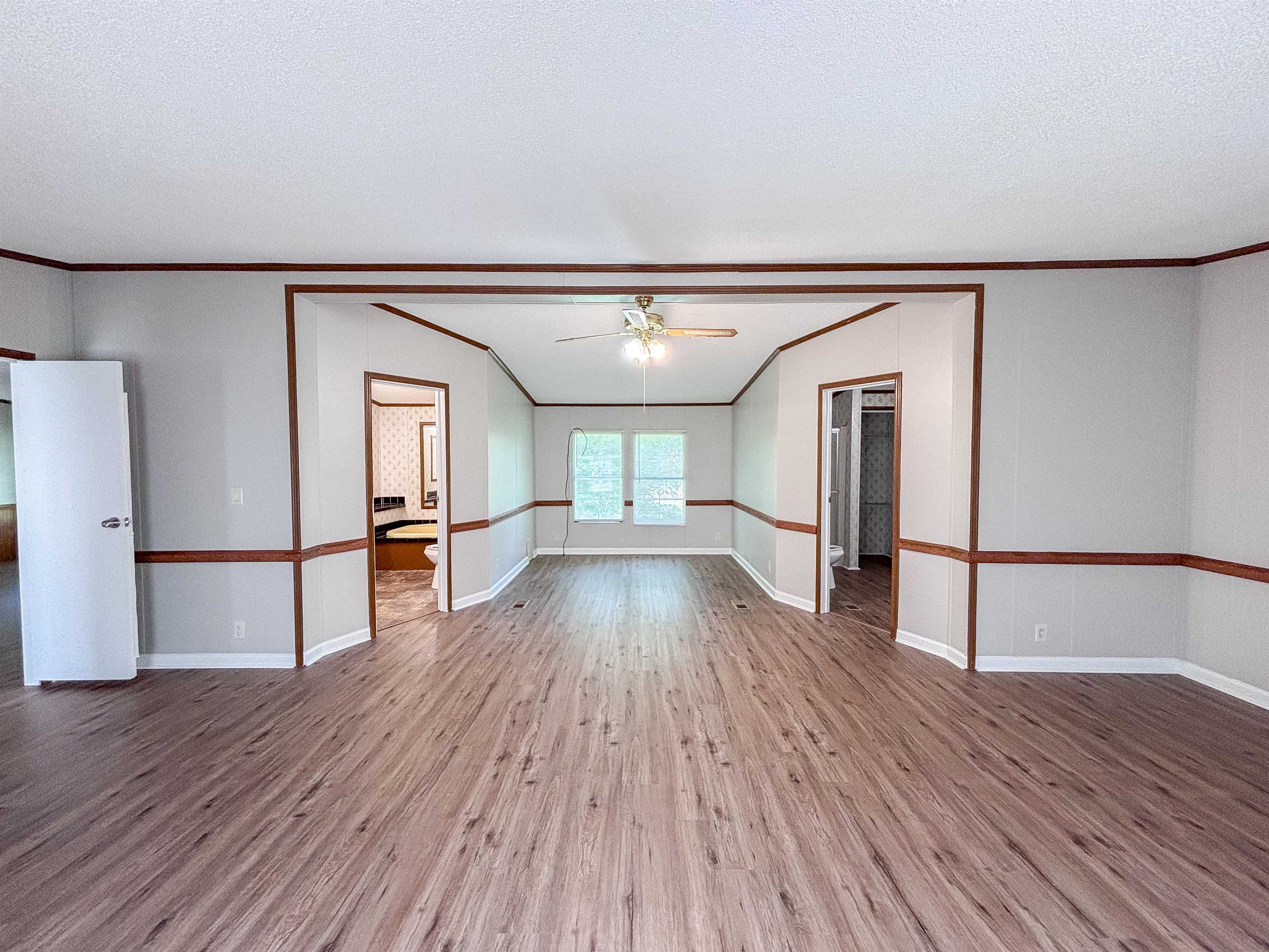 2847 Holly Grove Road Covington, TN 38019 - Photo 15 of 36 Spacious interior featuring wood-finish flooring, light grey walls with wood trim, and a ceiling fan