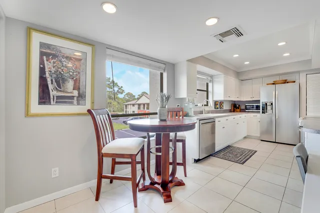 a kitchen with a dining table chairs cabinets and stainless steel appliances