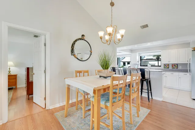 a view of a dining room and livingroom with furniture wooden floor a chandelier