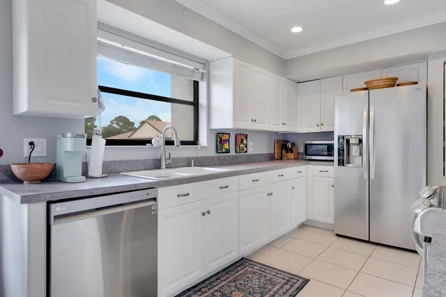 a kitchen with stainless steel appliances a sink cabinets and a window