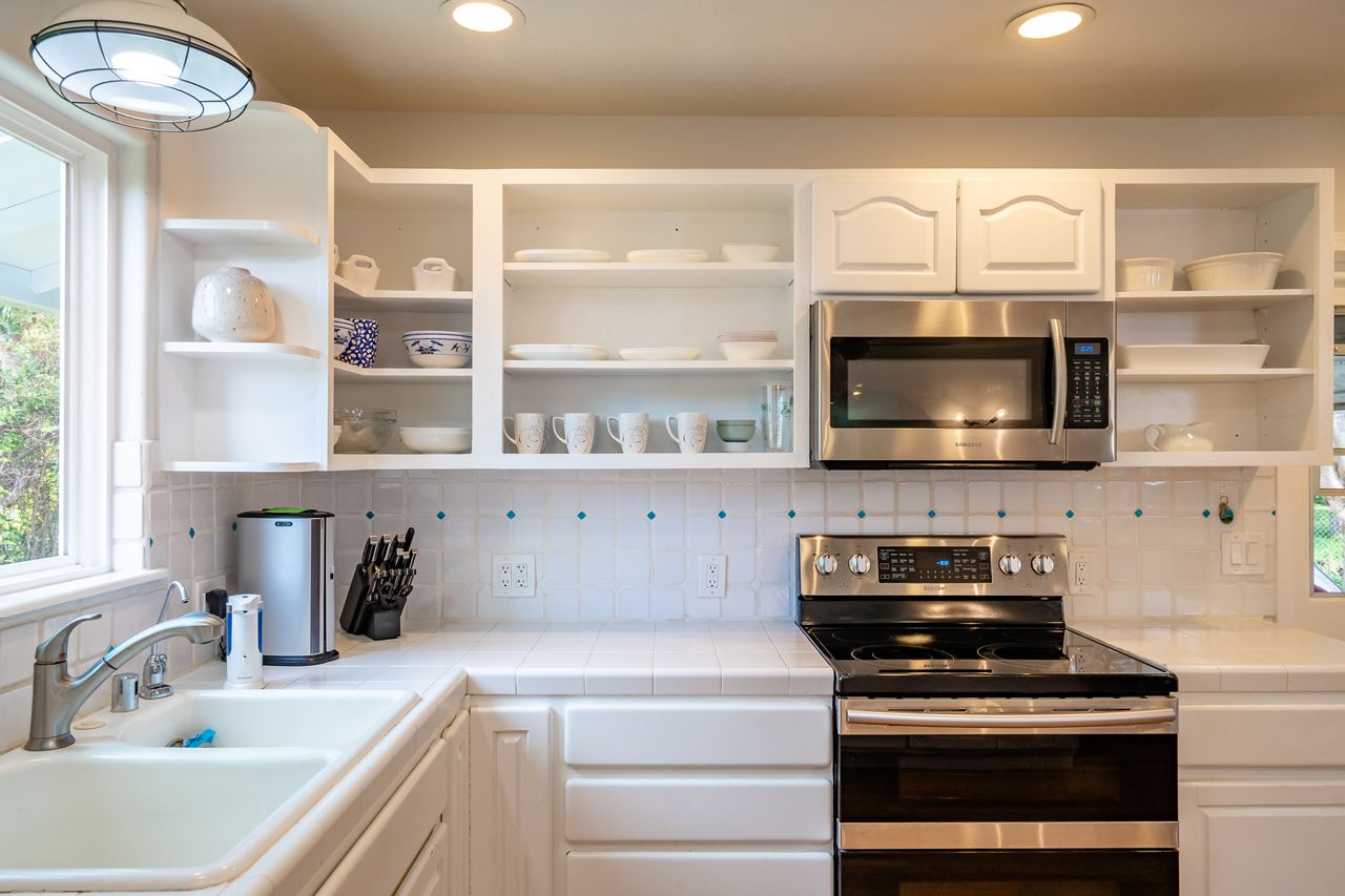 467 Ulumalu Road Haiku, HI 96708 - Photo 11 of 30 a kitchen with stainless steel appliances a stove a microwave and wooden cabinets
