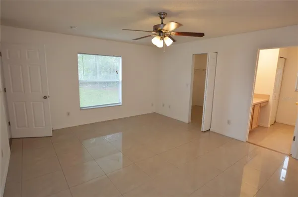 an empty room with chandelier fan and windows