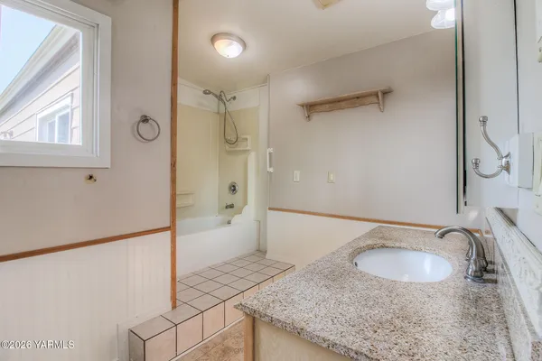 a bathroom with a granite countertop sink a mirror and shower
