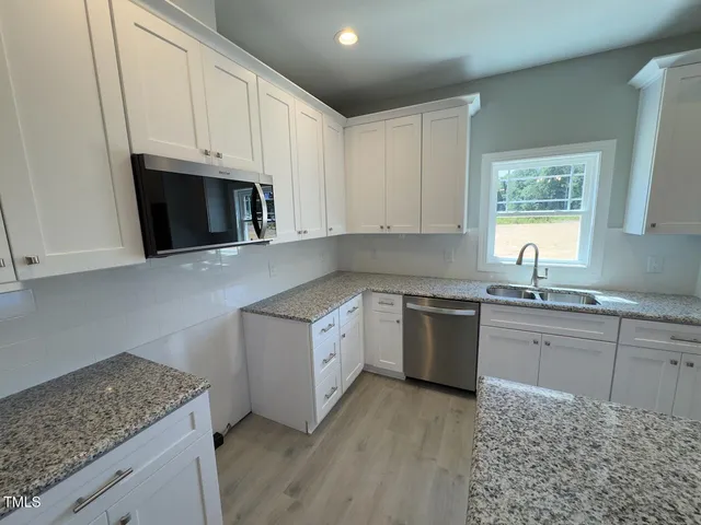 a kitchen with granite countertop white cabinets and white appliances