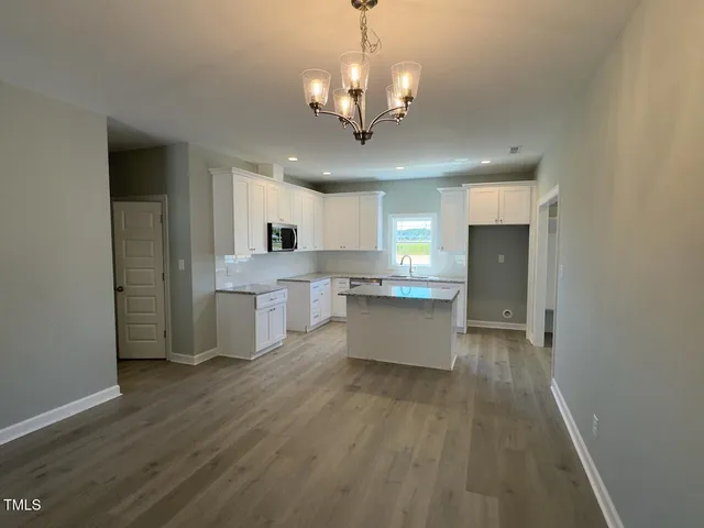 a large kitchen with stainless steel appliances granite countertop a stove top oven a sink dishwasher and a refrigerator with wooden floor