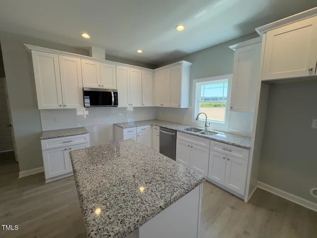 a kitchen with kitchen island granite countertop a sink and a stove top oven