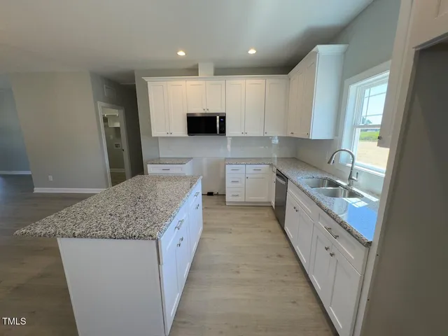 a large kitchen with stainless steel appliances kitchen island granite countertop a sink and cabinets