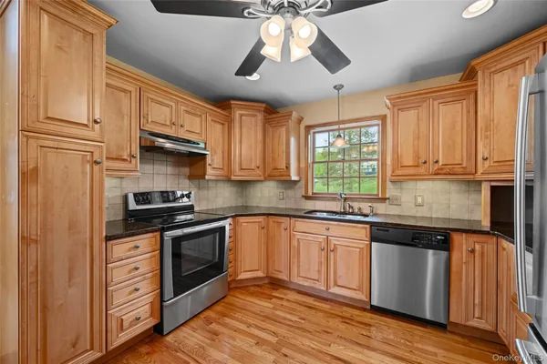a kitchen with stainless steel appliances granite countertop a sink cabinets and wooden floor