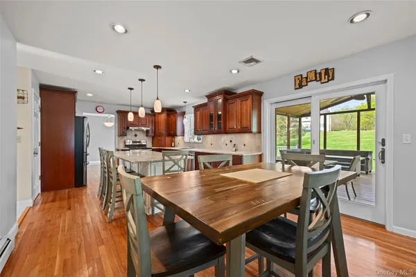 a kitchen with stainless steel appliances kitchen island granite countertop a stove a refrigerator a oven and a sink with wooden floor