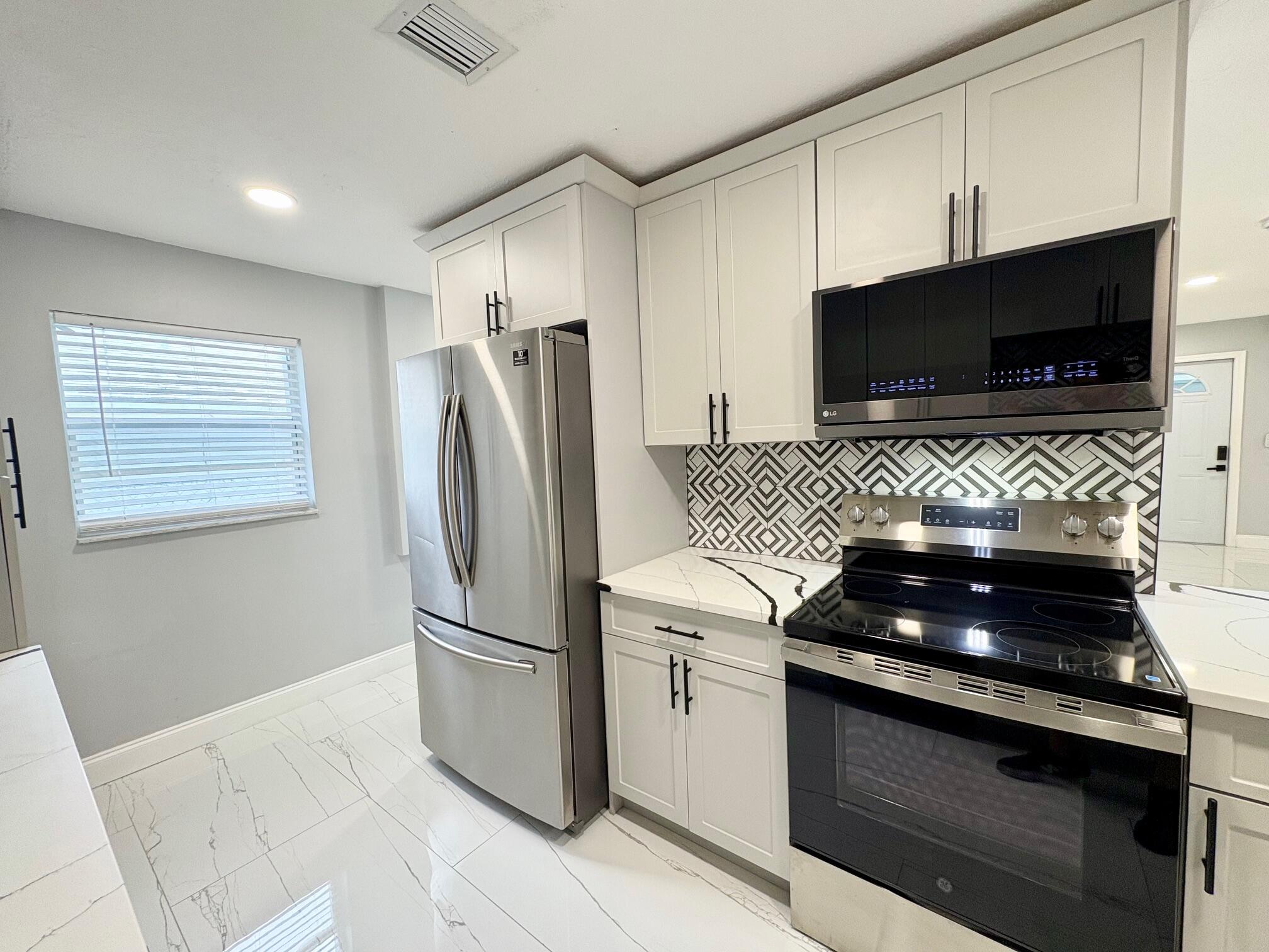 1733 Sunset Avenue Lake Worth Beach, FL 33460 - Photo 11 of 19 a kitchen with granite countertop a refrigerator and a stove top oven