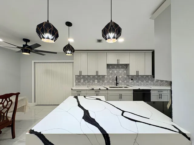 a kitchen with stainless steel appliances a stove a chandelier and chairs