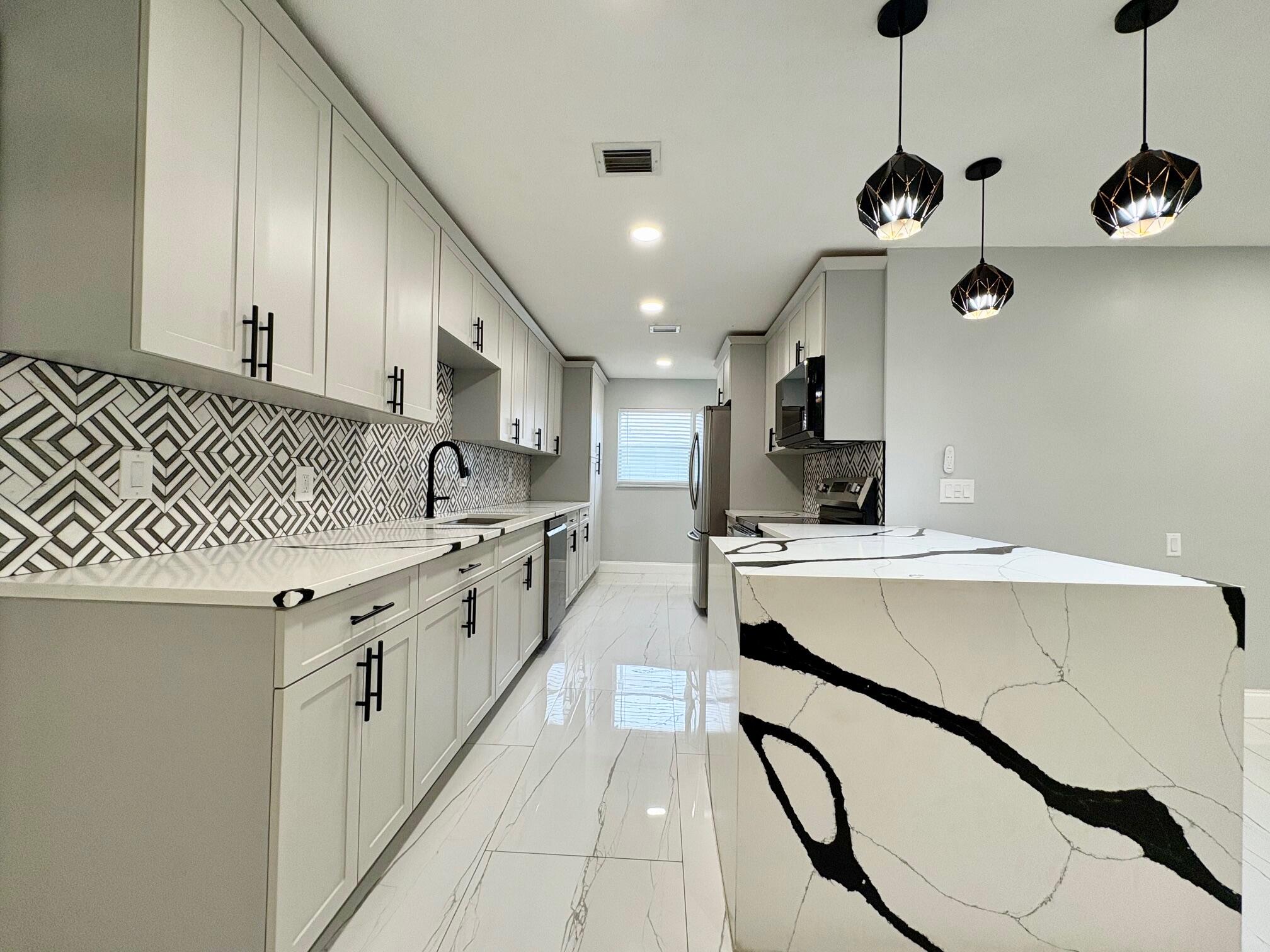 1733 Sunset Avenue Lake Worth Beach, FL 33460 - Photo 7 of 19 a kitchen with stainless steel appliances granite countertop a sink a stove and a refrigerator