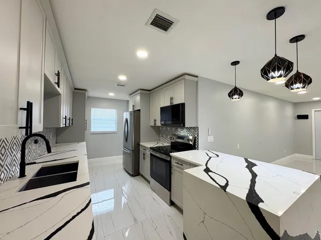 a kitchen with granite countertop a sink stainless steel appliances and white cabinets