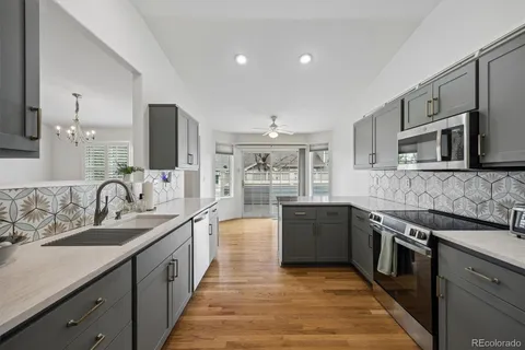 a large kitchen with stainless steel appliances granite countertop a sink and dishwasher a stove top oven with wooden floor