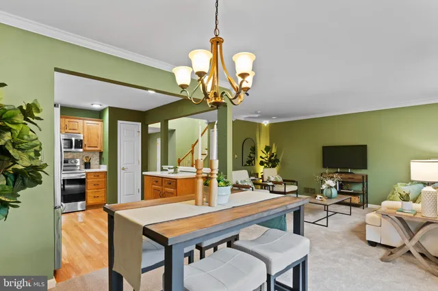 a dining room with wooden floor a chandelier a wooden table and chairs