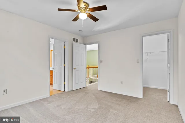 an empty room with closet and a chandelier fan