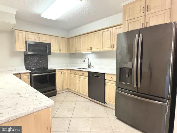 a kitchen with granite countertop a refrigerator and a sink