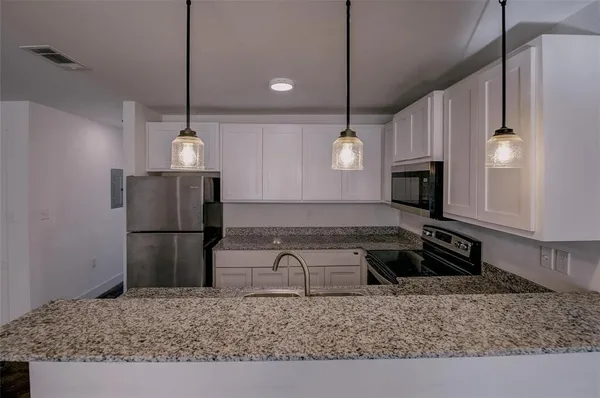 a kitchen with kitchen island granite countertop a stove a refrigerator and a sink with wooden floor