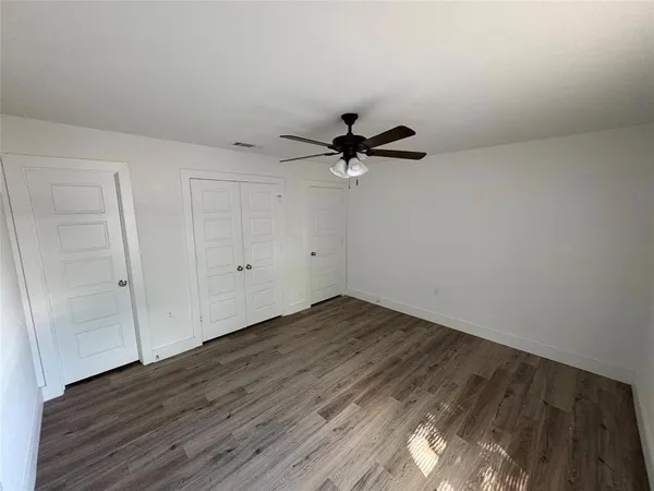 a view of a room with wooden floor and a ceiling fan
