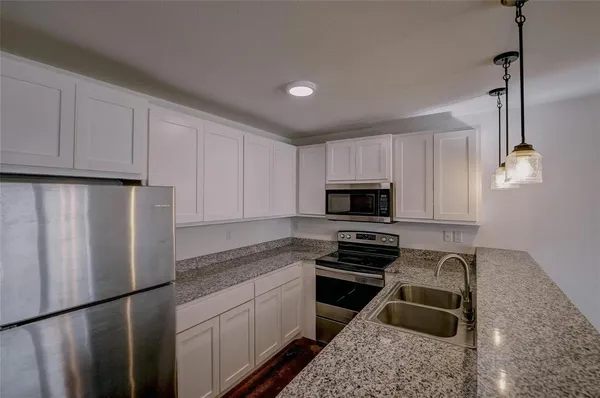 a kitchen with granite countertop a refrigerator stove and sink