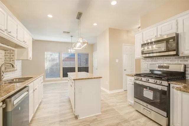 a kitchen with stainless steel appliances granite countertop a stove a sink and a refrigerator