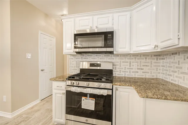 a kitchen with granite countertop a stove top oven microwave and cabinets
