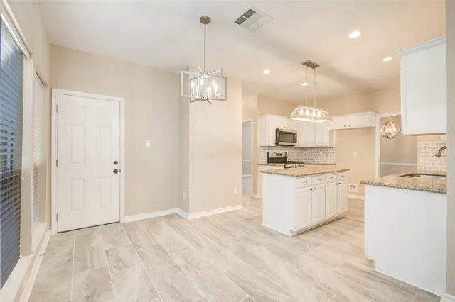 a kitchen with kitchen island granite countertop appliances cabinets and a sink