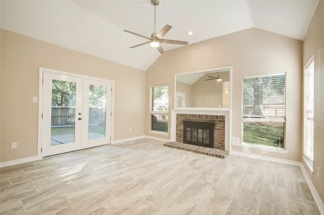 an empty room with fireplace fan and windows