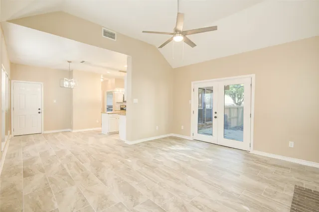 a view of an empty room with wooden floor and a ceiling fan
