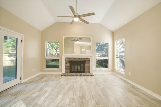 an empty room with windows fireplace and a ceiling fan