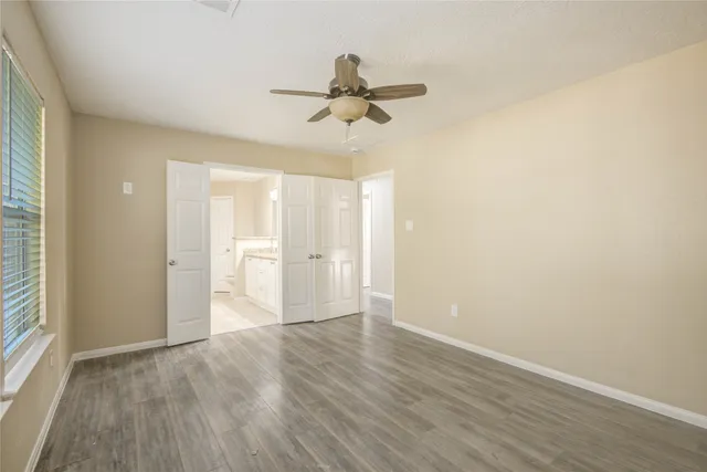 a view of empty room with wooden floor and fan
