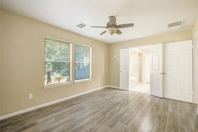 a view of an empty room with a window and wooden floor