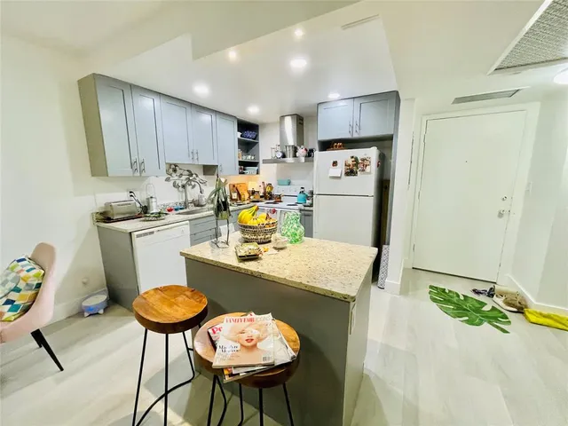 a kitchen with a sink a refrigerator and chairs
