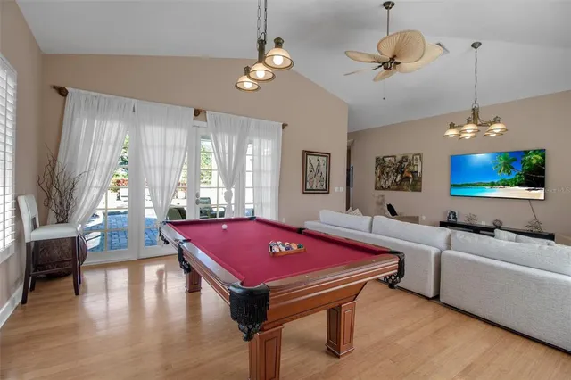 a living room with pool table flat screen tv and windows