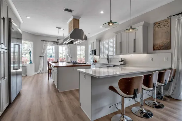 a kitchen with kitchen island a dining table chairs sink and wooden floor