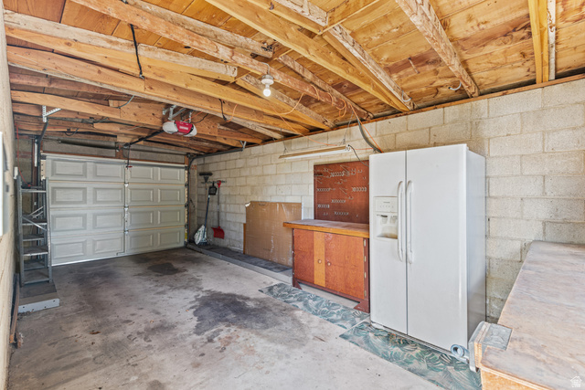 542 East 3400th Street North Provo, UT 84604 - Photo 29 of 39 Single-bay garage with concrete block walls, exposed wood beam ceiling, and a paneled garage door
