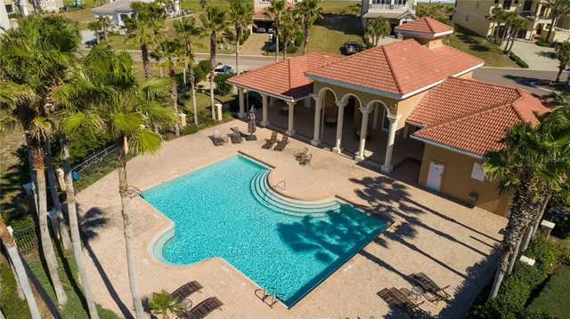 a view of swimming pool with a yard and palm trees