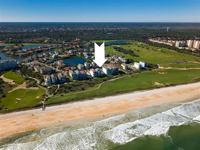 an aerial view of ocean and residential houses with outdoor space