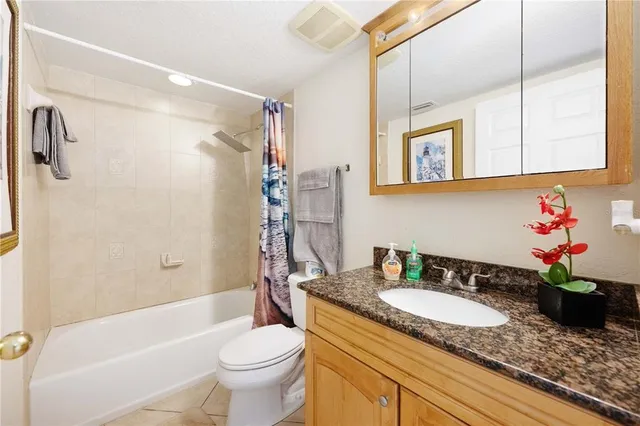 a bathroom with a granite countertop sink a toilet and shower