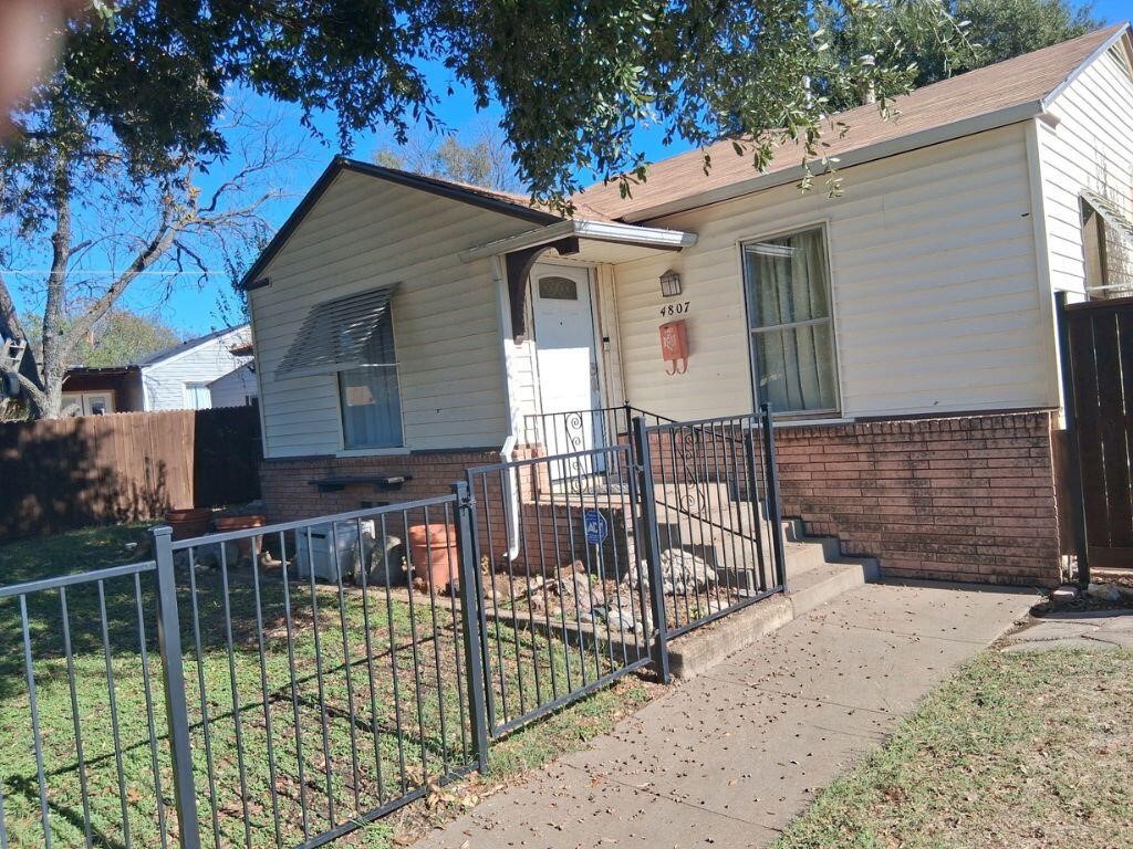 a view of house with a small yard and wooden fence and a large tree