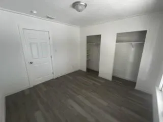 a view of an empty room with wooden floor and closet