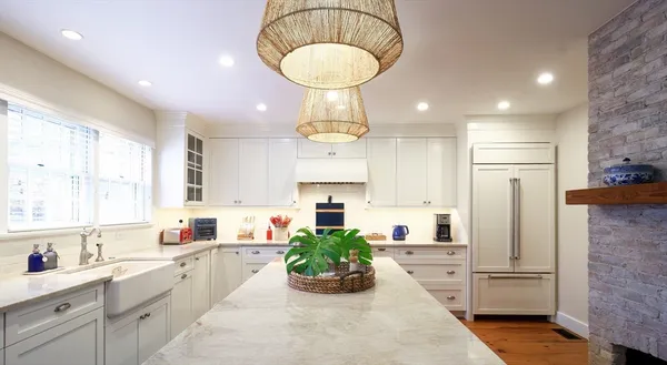 a kitchen with stainless steel appliances granite countertop a refrigerator a sink dishwasher and white cabinets with wooden floor