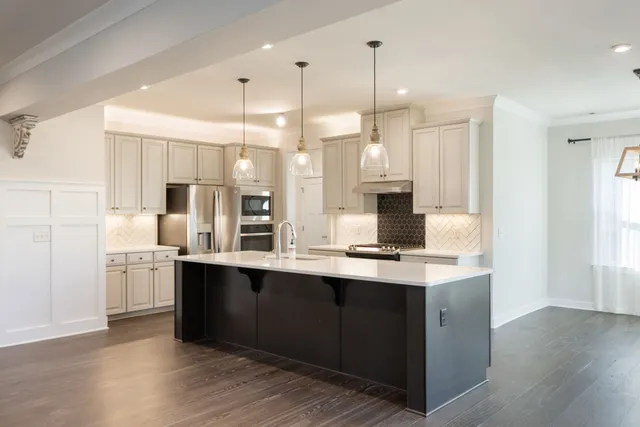 a view of a livingroom with a ceiling fan & kitchen space
