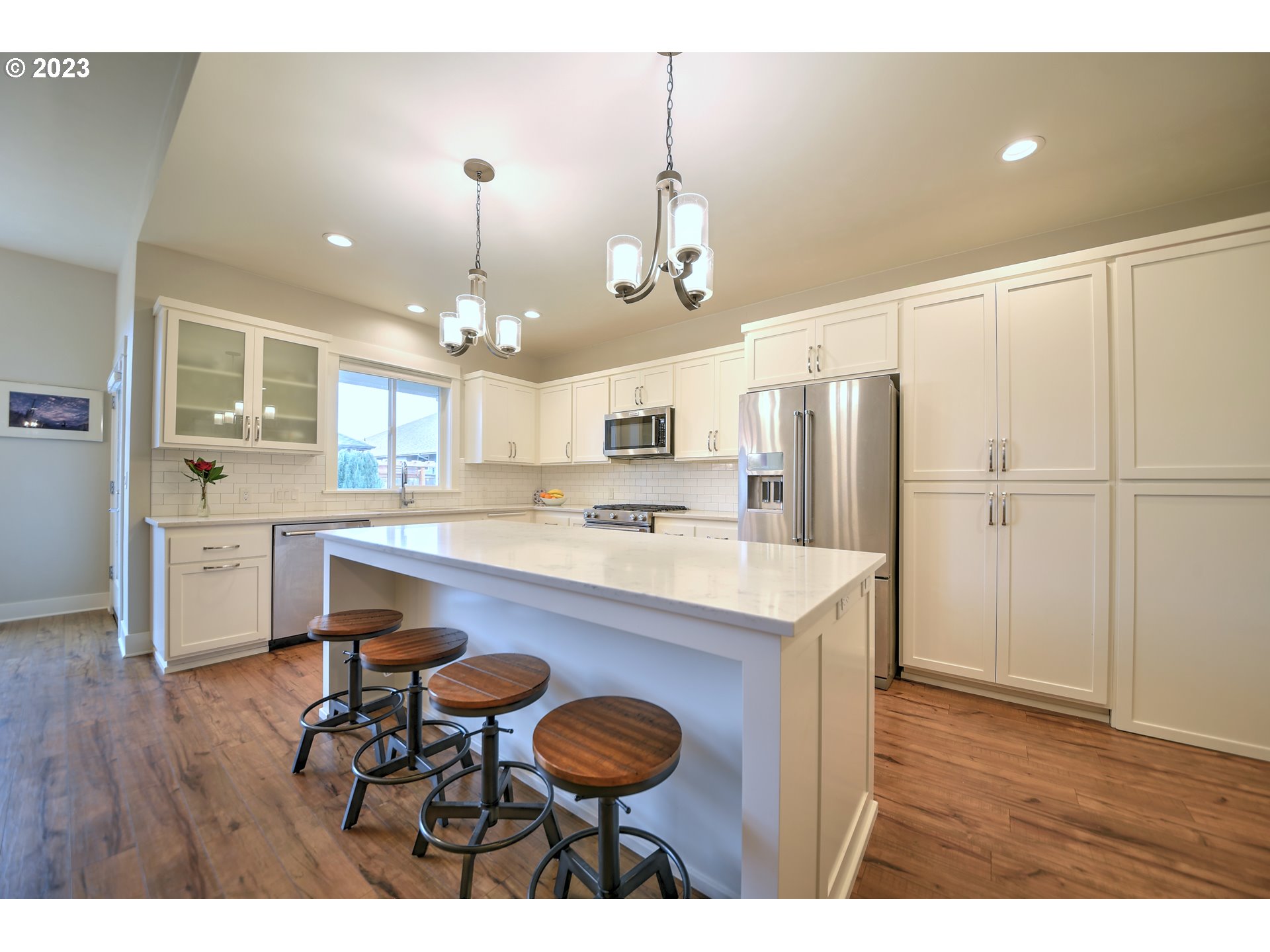 851 Hamilton Street Springfield, OR 97477 - Photo 4 of 31 a kitchen with kitchen island a stove a refrigerator and a dining table with wooden floors
