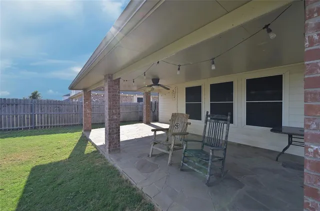 a view of a patio with table and chairs and wooden fence