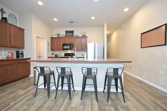 a kitchen with stainless steel appliances a microwave a sink a stove a refrigerator cabinets and wooden floor