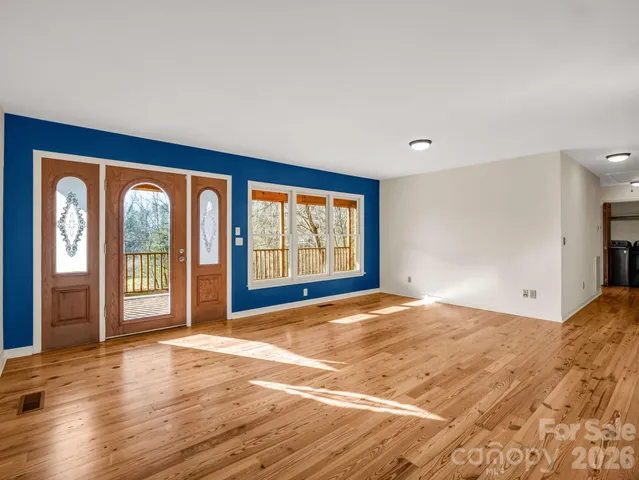 a view of an empty room with a window and wooden floor