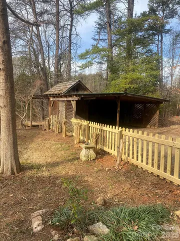 a view of backyard with wooden fence and a large tree