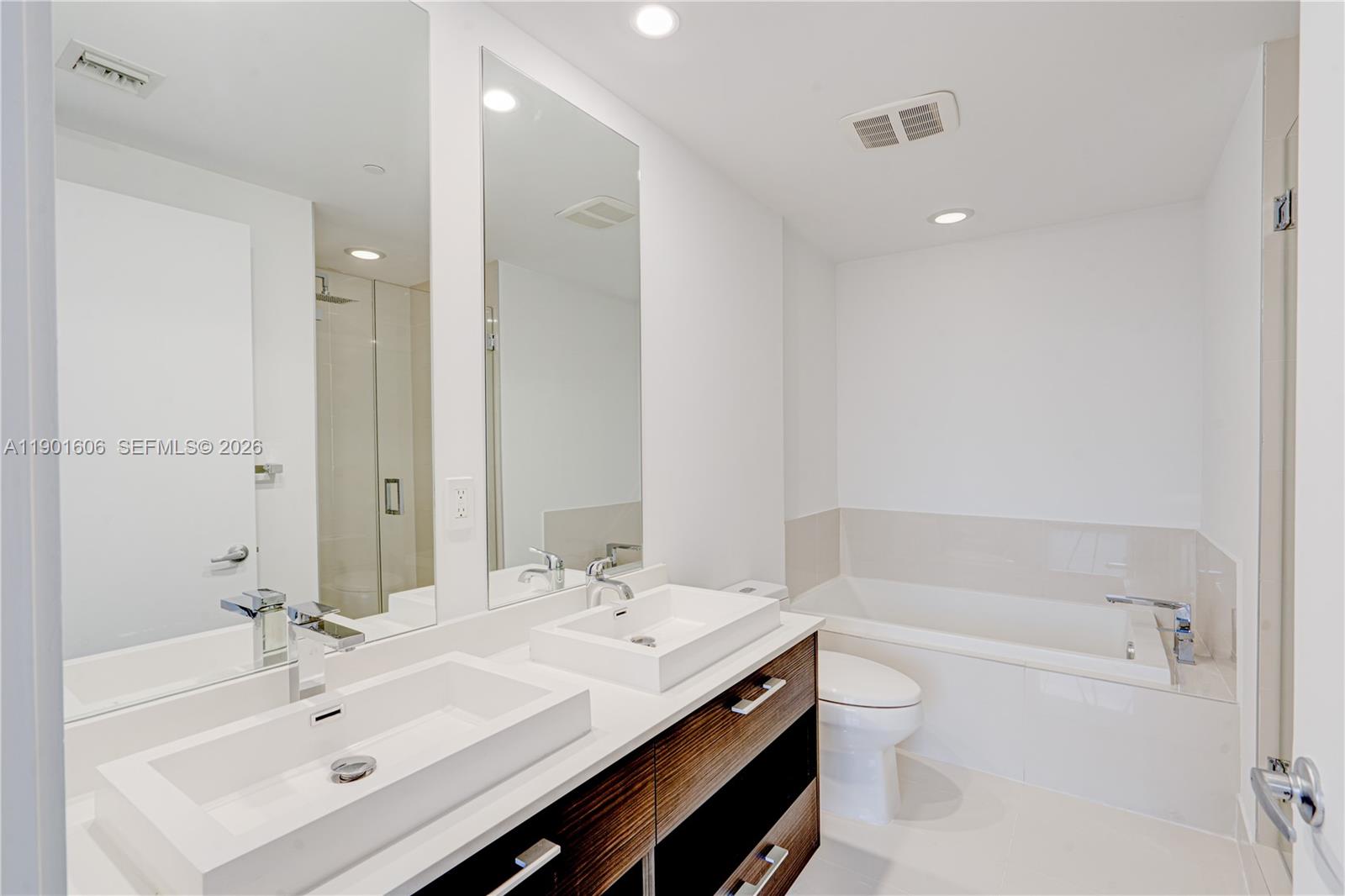 45 Southwest 9th Street, Unit 2408 Miami, FL 33130 - Photo 11 of 37 a bathroom with a bathtub shower sink and a mirror