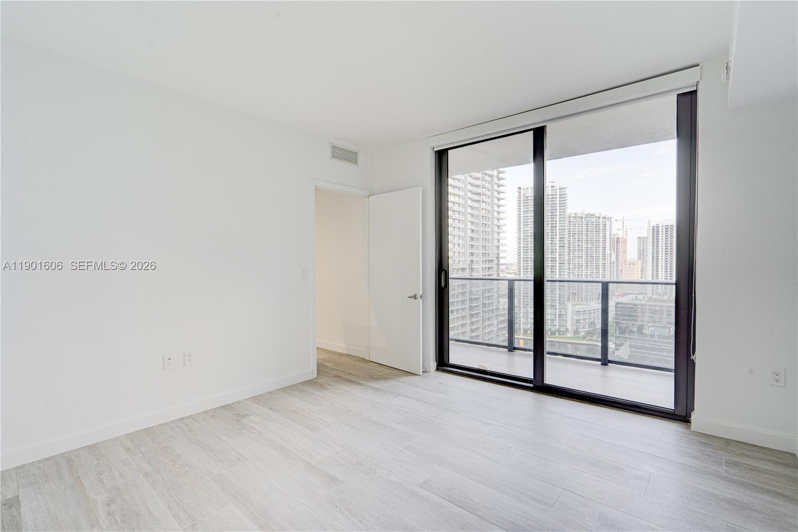 45 Southwest 9th Street, Unit 2408 Miami, FL 33130 - Photo 10 of 37 an empty room with wooden floor and sliding glass door